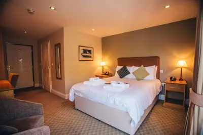 a bedroom with a large bed with two towels on it at Tynycornel Hotel in Tal-y-llyn
