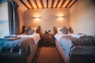a small room with two beds and a night stand at Tynycornel Hotel in Tal-y-llyn