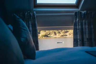 a bedroom with a window with a view of a body of water at Tynycornel Hotel in Tal-y-llyn