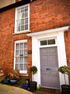 a brick house with a gray door and two windows at Beautiful stylish 2 bed apartment with free parking in Ludlow