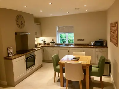 a kitchen with a wooden table and green chairs at Beautiful stylish 2 bed apartment with free parking in Ludlow