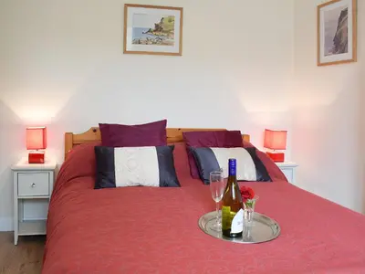 a bedroom with a red bed with a bottle of wine at Glasfor in Llanon