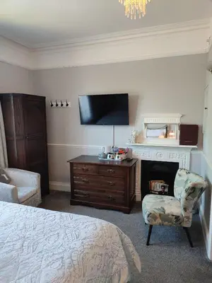 a bedroom with a bed and a chair and a tv at Anton Guest House Bed and Breakfast in Shrewsbury