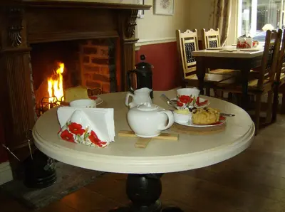 a table with a tea set on it with a fireplace at The Poppy House in Bishops Castle