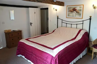 a bedroom with a large bed with a purple blanket at The Poppy House in Bishops Castle