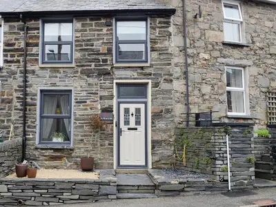 a stone house with a white door and windows at Tŷ Ar Y Tro in Tanygrisiau