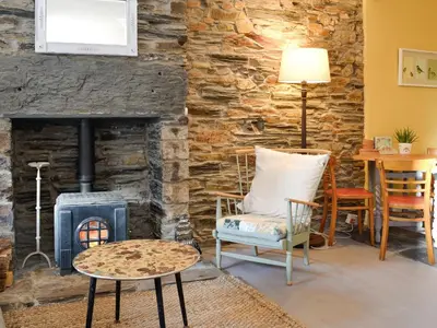 a living room with a stone wall and a wood stove at Tŷ Ar Y Tro in Tanygrisiau