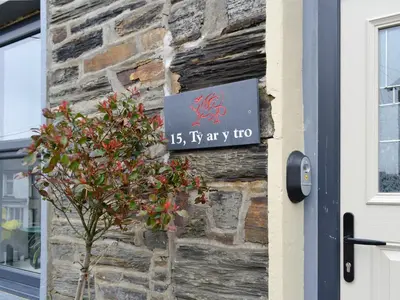 a sign on the side of a building next to a tree at Tŷ Ar Y Tro in Tanygrisiau