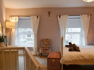 a bedroom with a bed and a chair and windows at Tŷ Ar Y Tro in Tanygrisiau