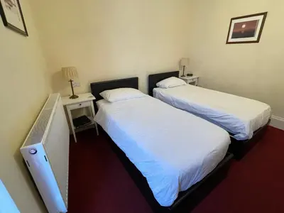two beds in a hotel room with a tv at Môr Wyn Guest House in Barmouth