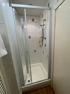 a shower with a glass door in a bathroom at Môr Wyn Guest House in Barmouth