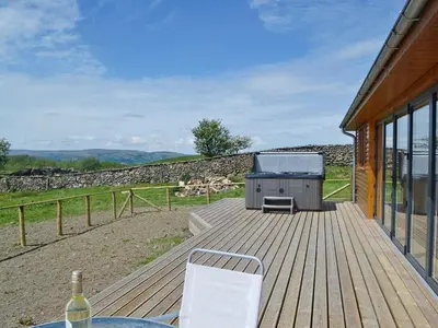 a deck with a grill on the side of a house at Bluebell Lodge in Llandrindod Wells