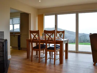 a dining room with a table and chairs with a view at Bluebell Lodge in Llandrindod Wells