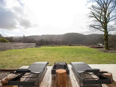 a wooden deck with two beds and a field at The Pendre Longbarn in Pentre-briwnant