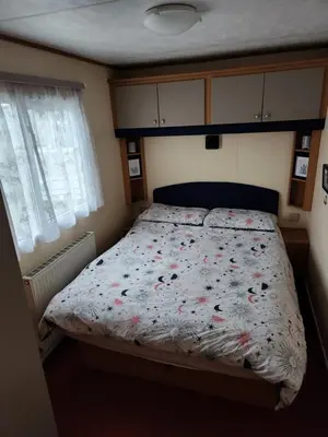 a bedroom with a bed with flowers on it at 92 Barmouth Bay Holiday Park in Llanddwywe