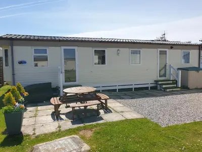 a picnic table in front of a house at 92 Barmouth Bay Holiday Park in Llanddwywe