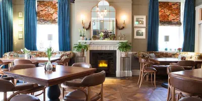 a restaurant with tables and chairs and a fireplace at Royal Ship in Dolgellau
