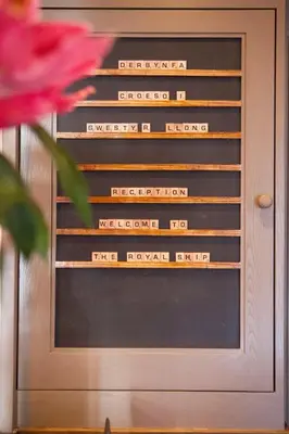a door with words on it with a flower at Royal Ship in Dolgellau