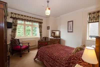 a bedroom with a bed and a chair and a window at Ardwyn House in Llanwrtyd Wells