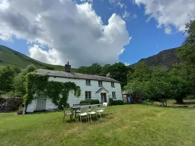 a table and chairs in front of a white house at Gesail Barn and Farmhouse in Machynlleth