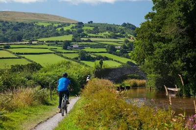 a person riding a bike on a path near a river at Ty Newydd B&B in Brecon