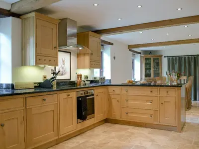 a kitchen with wooden cabinets and black counter tops at The Oak in Newchurch