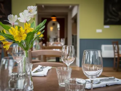 a table with wine glasses and a vase of flowers at The Cliffe at Dinham in Ludlow