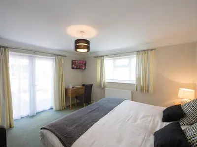 a bedroom with a bed and a desk and windows at The Cliffe at Dinham in Ludlow