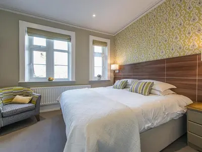 a bedroom with a large white bed and two windows at The Cliffe at Dinham in Ludlow