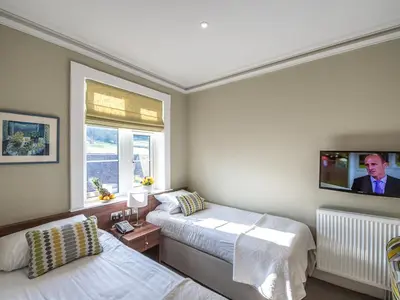 a bedroom with two beds and a tv on the wall at The Cliffe at Dinham in Ludlow