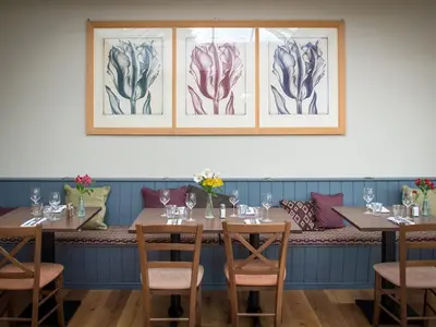 a dining room with tables and chairs and paintings on the wall at The Cliffe at Dinham in Ludlow