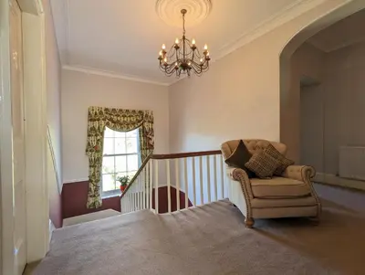 a living room with a chair and a chandelier at LLys Aeron 