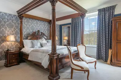 a bedroom with a canopy bed and a chair at LLys Aeron 
