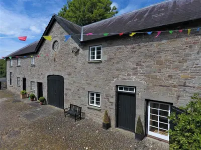 a brick building with flags on the side of it at Glanhenwye Courtyard Cottages in Glasbury