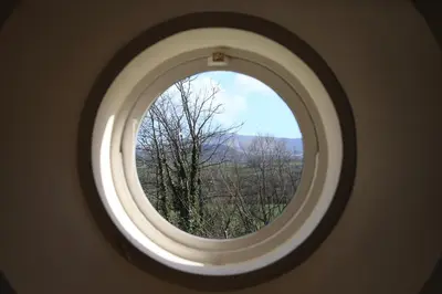 a round window in a room with a view of trees at Glanhenwye Courtyard Cottages in Glasbury