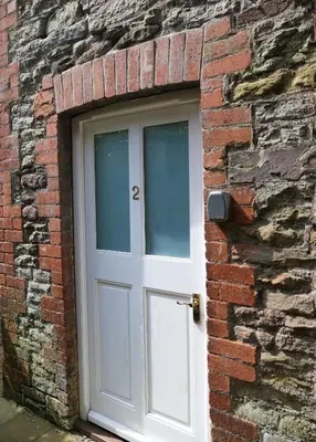 a white door in a brick wall at 2 Bell Street in Talgarth