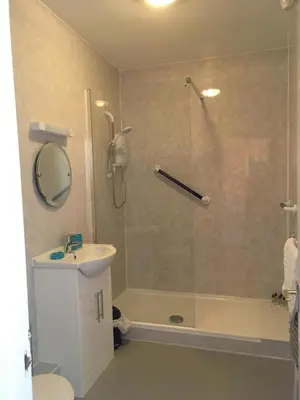 a bathroom with a shower and a toilet and a sink at Min y Mor Hotel in Barmouth