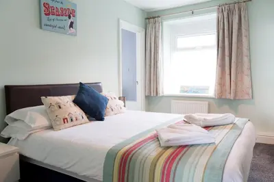 a bedroom with a bed with pillows and a window at Min y Mor Hotel in Barmouth