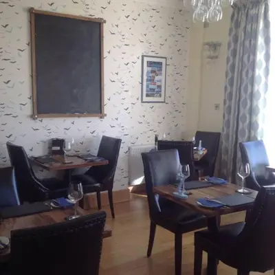 a restaurant with wooden tables and chairs and a chalkboard at Min y Mor Hotel in Barmouth