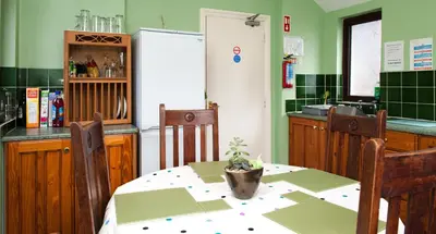 a kitchen with a table and chairs and a refrigerator at Rooms by Maes y mor Town Centre in Aberystwyth