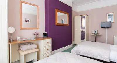 a bedroom with two beds and a purple wall at Rooms by Maes y mor Town Centre in Aberystwyth