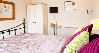 a bedroom with a bed with pink sheets and a mirror at Rooms by Maes y mor Town Centre in Aberystwyth