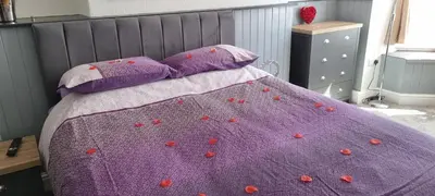 a bed with a purple blanket with red flowers on it at Rooms by Maes y mor Town Centre in Aberystwyth
