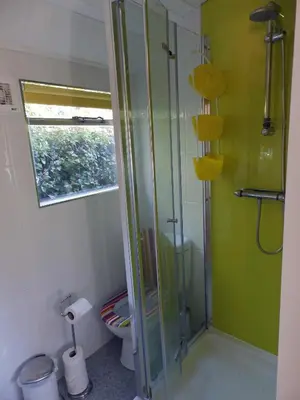a bathroom with a glass shower with a toilet at Showman's Wagon at Coed Cae in Dolgellau
