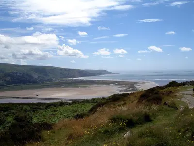 a view of a beach and the ocean from a hill at Showman's Wagon at Coed Cae in Dolgellau