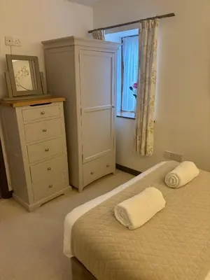 a bedroom with a bed and a dresser and a window at The Milking Parlour in Aberystwyth