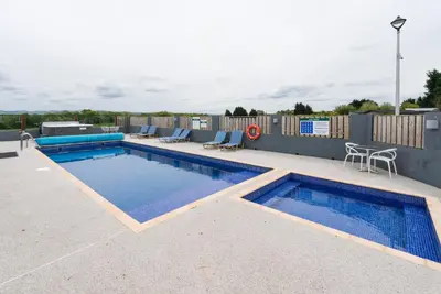 a swimming pool on a patio with two chairs around it at The Milking Parlour in Aberystwyth