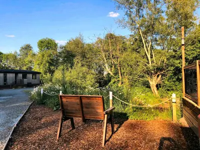 a wooden bench sitting in front of a garden at Alder River Lodge Clun Valley Luxury Hot Tub Break in Craven Arms