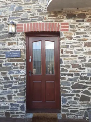 a door to a stone building with a dog sitting in the window at The Stores in Aberystwyth