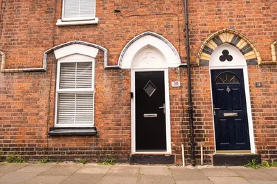 two black doors on a brick building with windows at Rose Cottage in Shrewsbury